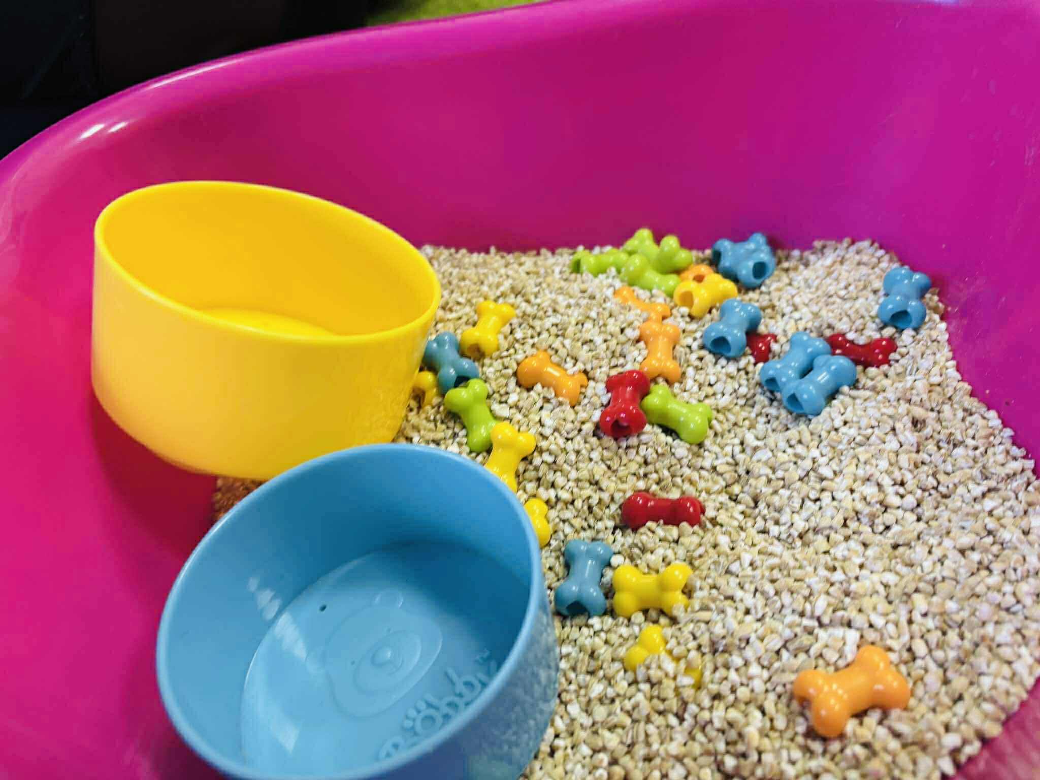 różowa misa z kaszą i kolorowymi elementami – terapia dotykowa, SI